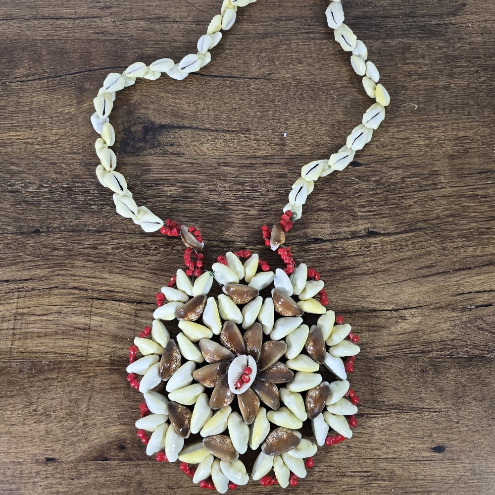 handmade cowrie shell necklace featuring a large, ornate circular pendant